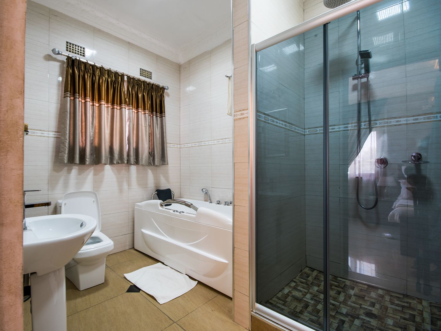 A bathroom with a toilet, sink, bathtub, and a glass-enclosed shower area.