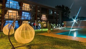 A hotel pool area with a fountain, outdoor seating, and a building with multiple balconies. - Sherbourne Hotel (Kitwe)