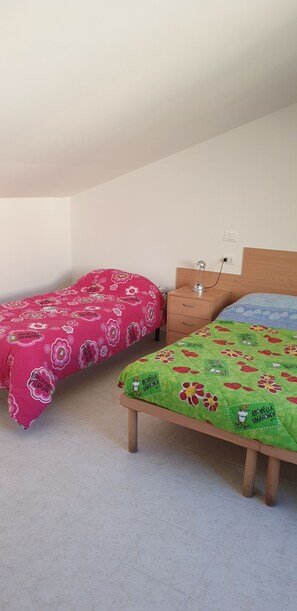 Two single beds with floral bedding, a bedside table with a lamp, and a power outlet on the wall. - Le ACACIE rooms ( ex B&B ) (Termoli)