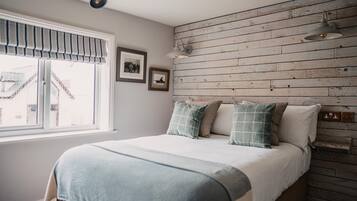Un dormitorio con cama, ventana con vistas, pared de madera y una lámpara en el techo.