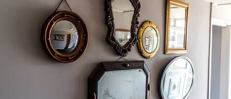 A wall with five mirrors of varying shapes and sizes.