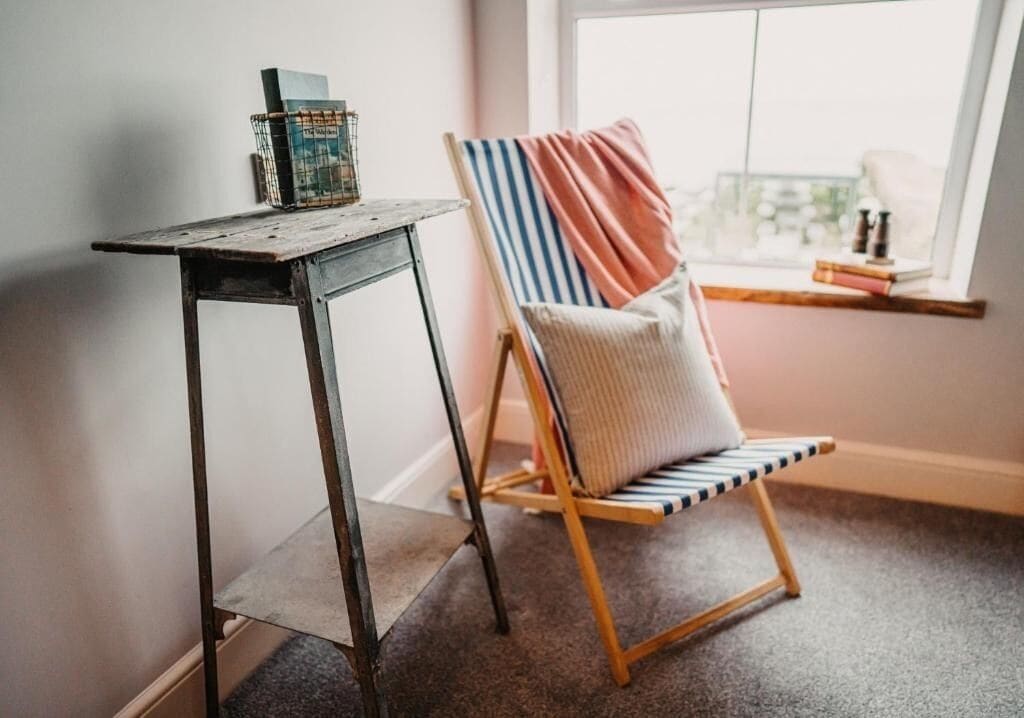 A corner with a wooden table, a striped chair, and a window with a view.
