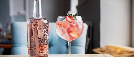 Una botella de whisky Laird's Carolina del Norte junto a un vaso de bebida helada con fresas y menta.
