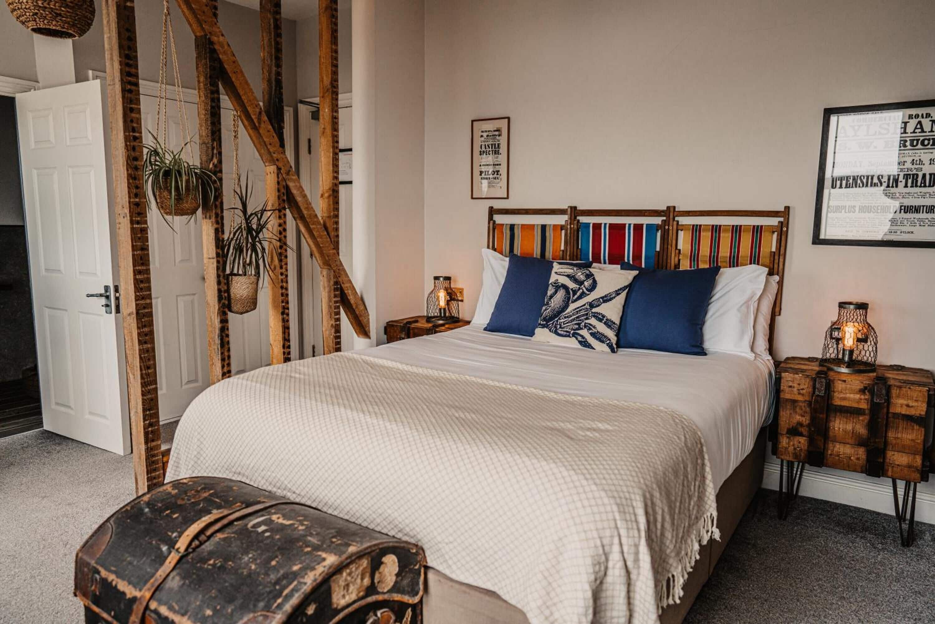 A bedroom with a bed, a wooden headboard, a nightstand, a lamp, and a suitcase.
