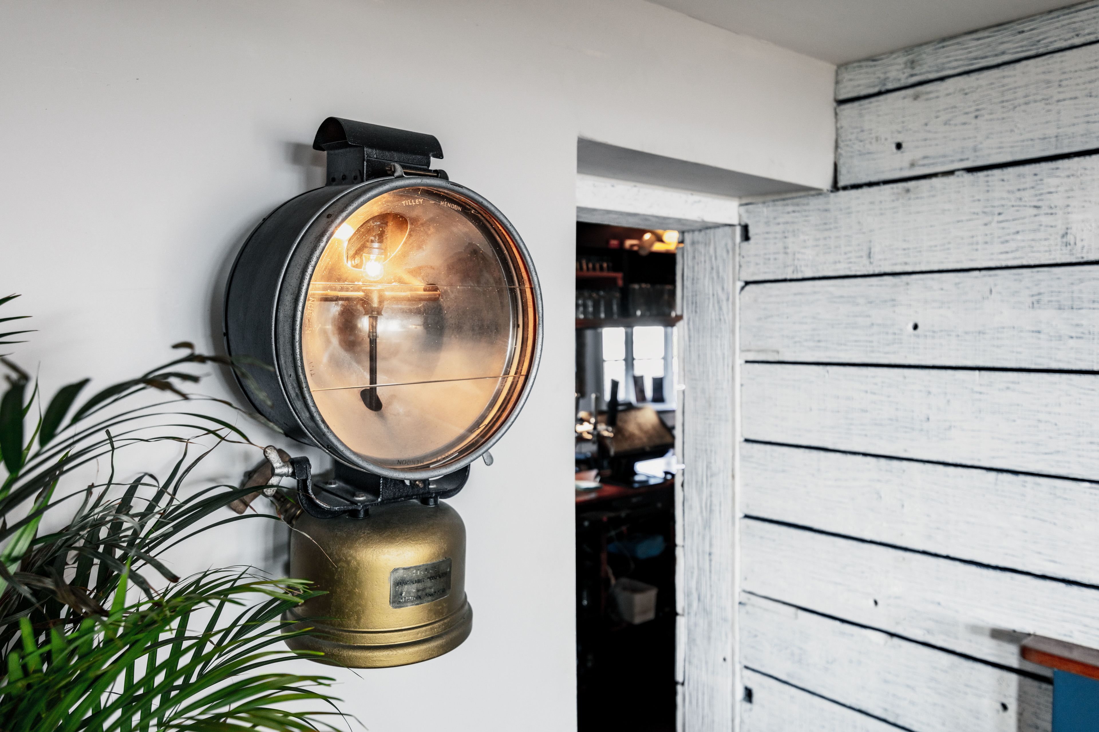 A wall-mounted light fixture with a brass base and a circular glass cover.