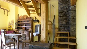 A rustic interior with a wooden staircase, a stone wall, and a dining area with a table and chairs. - La Tano Di Grich (Prazzo)