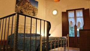 A bedroom with a bed, a wooden ceiling, a window with curtains, and a painting on the wall. - La Tano Di Grich (Prazzo)
