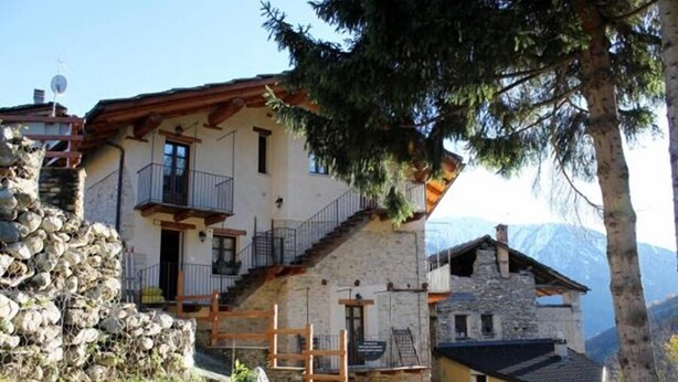 A two-story stone house with a wooden balcony, a stone staircase, and a mountain view. - La Tano Di Grich (Prazzo)