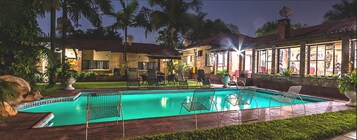 Una piscina al aire libre, sombrillas, sillones reclinables de piscina