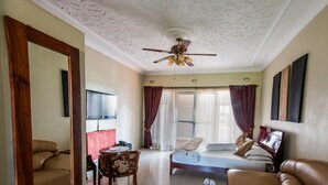 Une chambre d’hôtel équipée d’un lit, d’un canapé, d’une télévision, d’un ventilateur de plafond et d’un grand miroir.