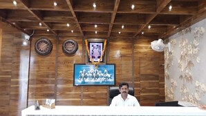A wooden reception desk with a clock, framed artwork, and a decorative garland.
