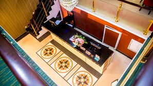 En hotellobby med en receptionsdisk, en kristallkrona och ett dekorativt mönster i golvet.