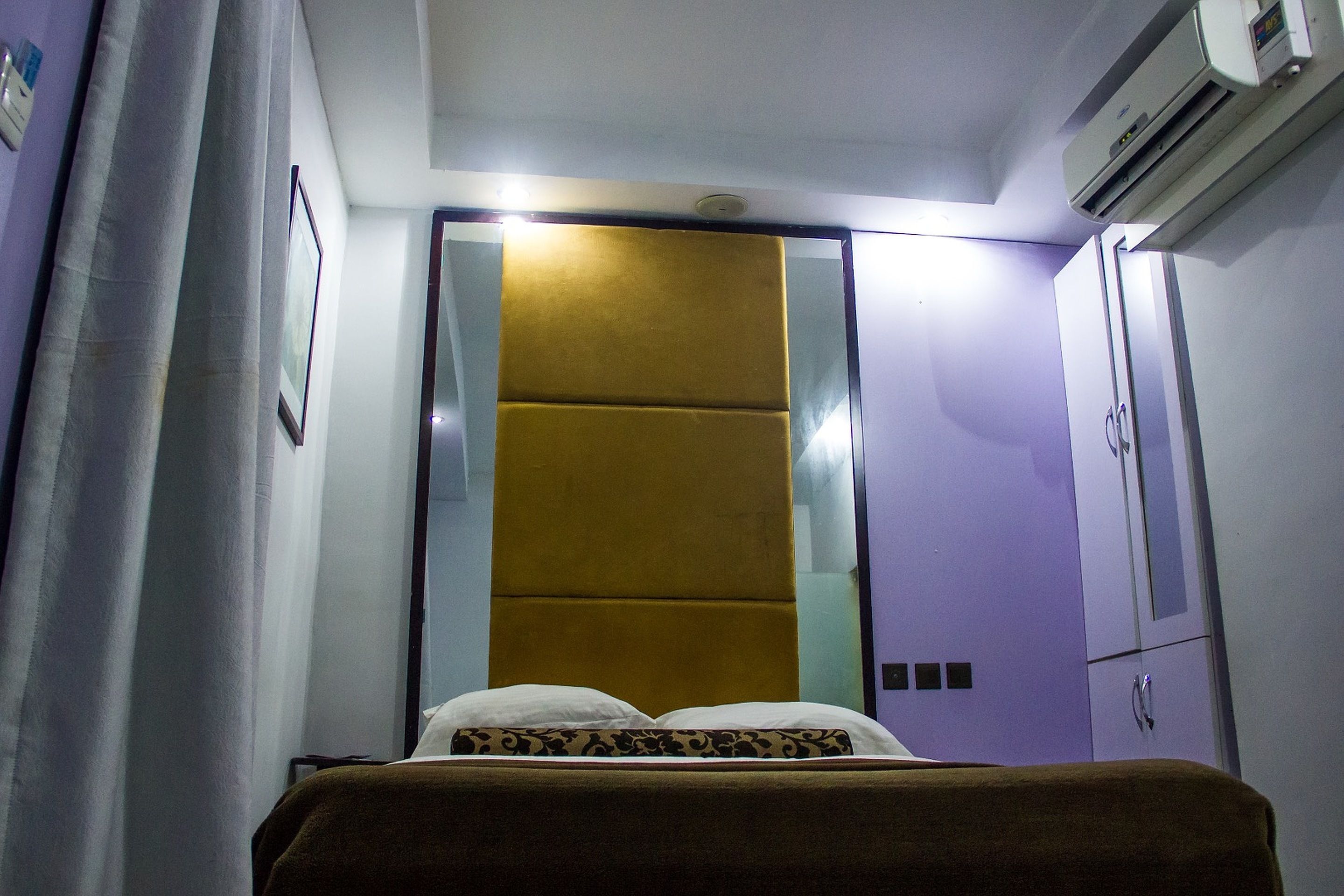 Un dormitorio con cama, armario y aire acondicionado.