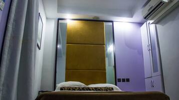Un dormitorio con cama, armario y aire acondicionado.