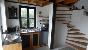 A kitchen with wooden cabinets, a double sink, and a window. - Kreta-Auszeit Ferienhaus Anidri (Kantanos-Selino)