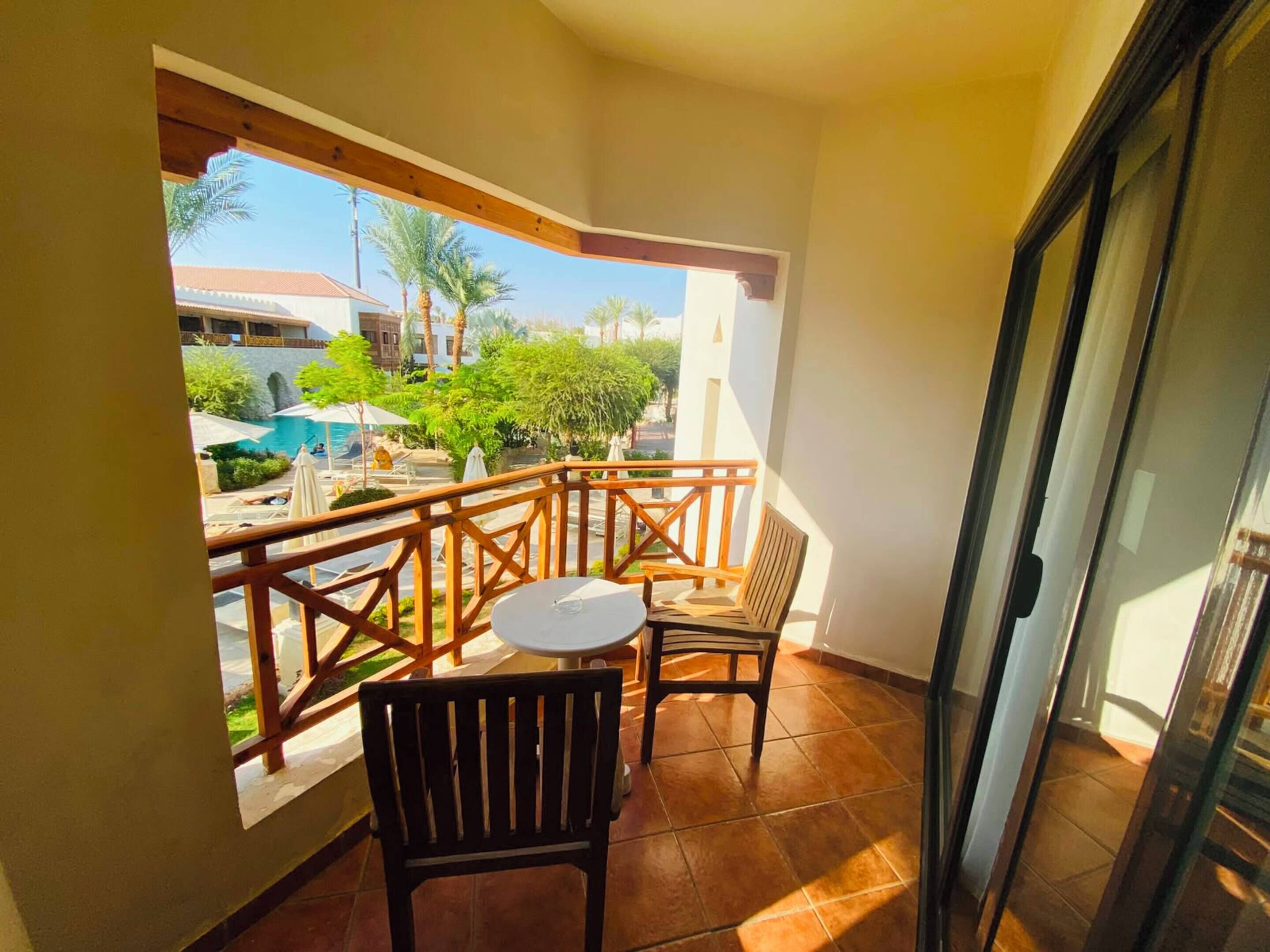 Un balcon avec une balustrade en bois, une petite table et deux chaises.