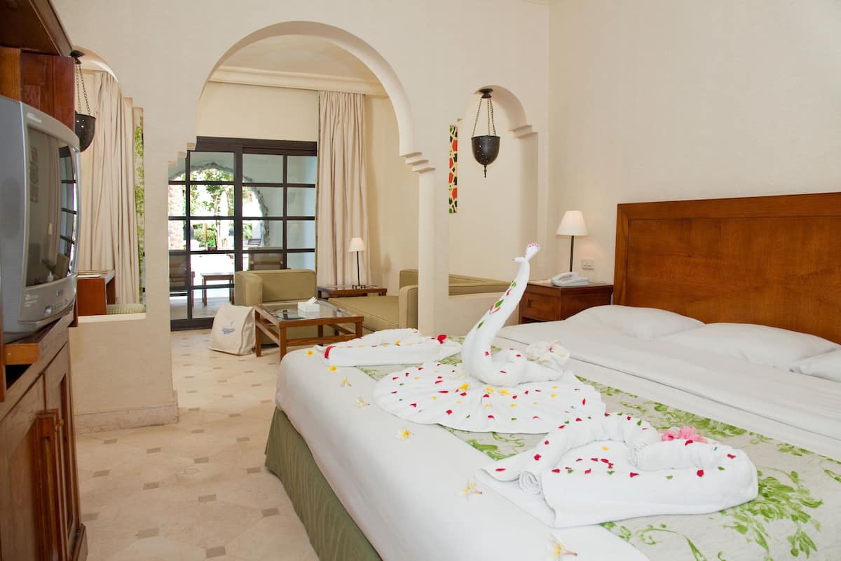 Quarto de hotel com cama, escrivaninha, cadeira, televisão e vista para o exterior.