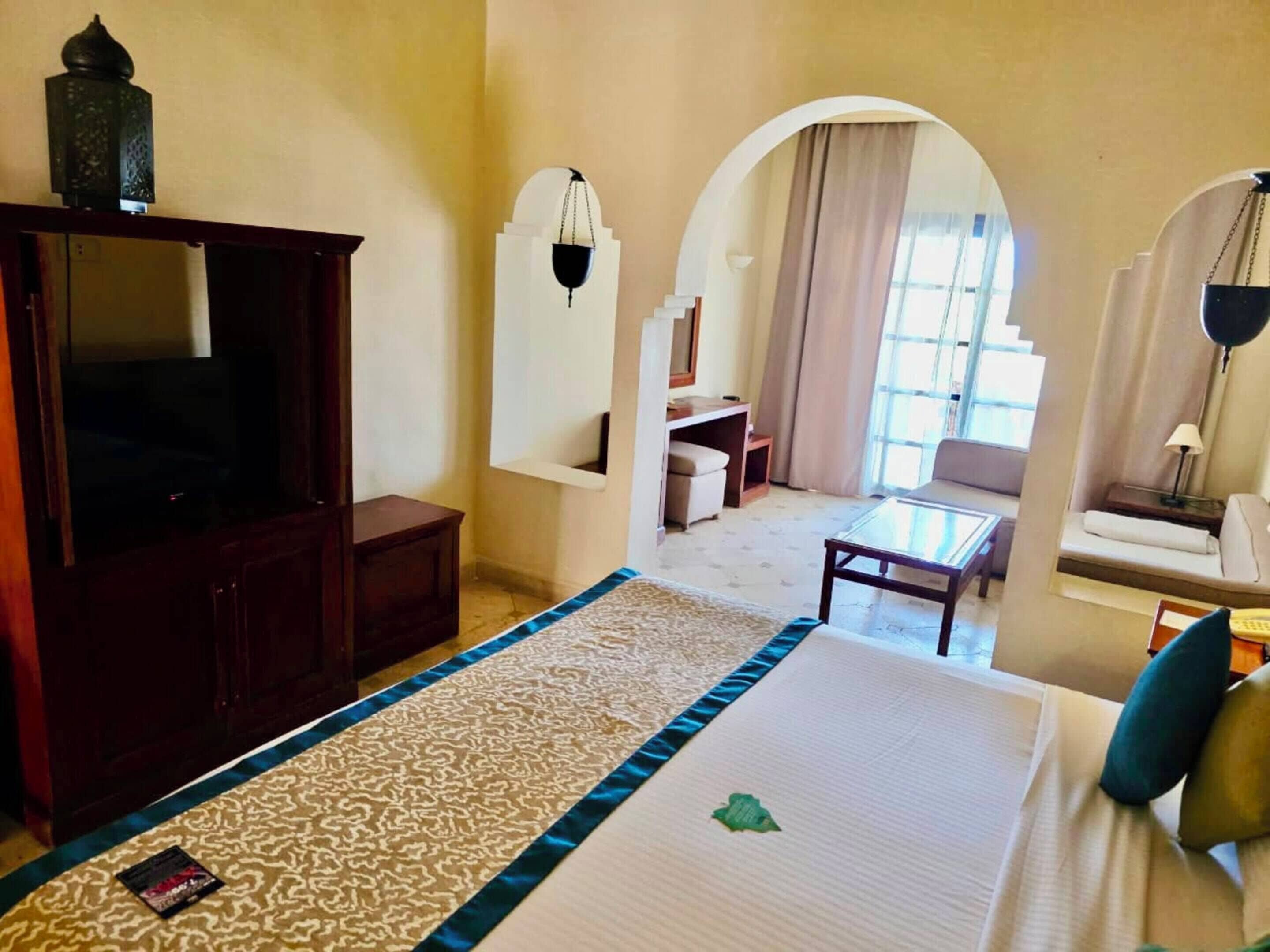 Una habitación de hotel con una cama grande, televisión, escritorio y sofá.