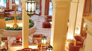 Eine geräumige Lobby mit Springbrunnen, Sitzbereichen und hängenden Laternen.