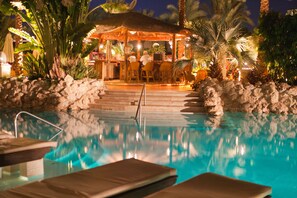 A pool area with lounge chairs, a bar, and a thatched-roof structure. - Ghazala Gardens  (Sharm El Sheikh)