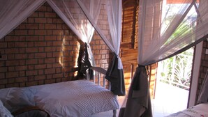 Un dormitorio con cama, una silla y ventana con vista a vegetación.