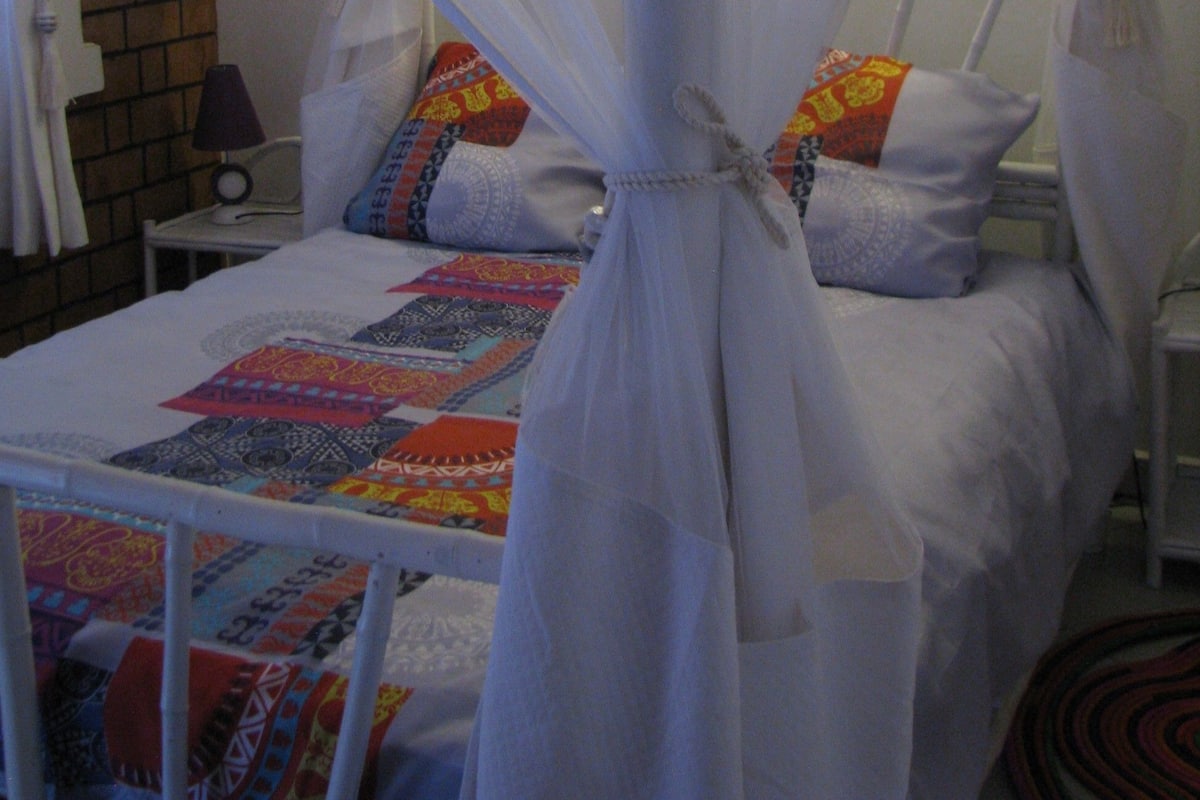 A bed with a canopy, pillows, a bedside table, and a lamp.