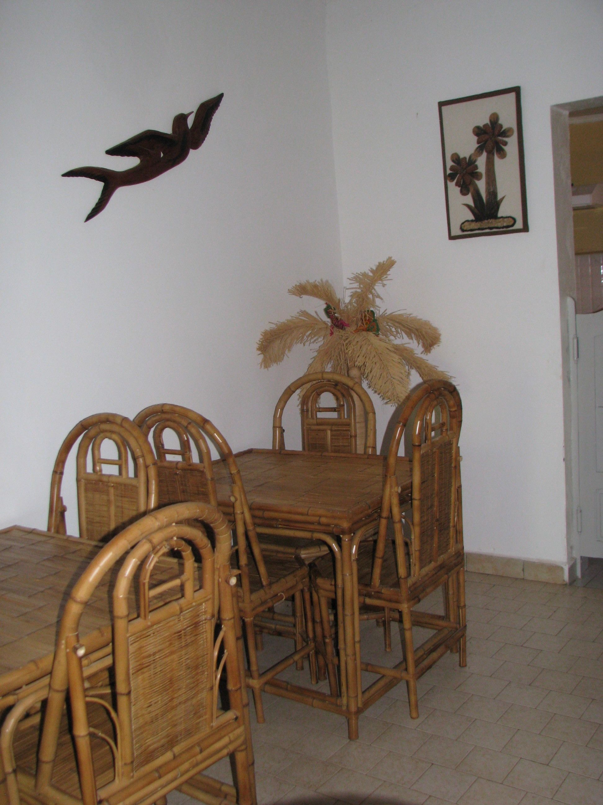 A dining area with a wooden table and chairs, a decorative wall hanging, and a framed picture.
