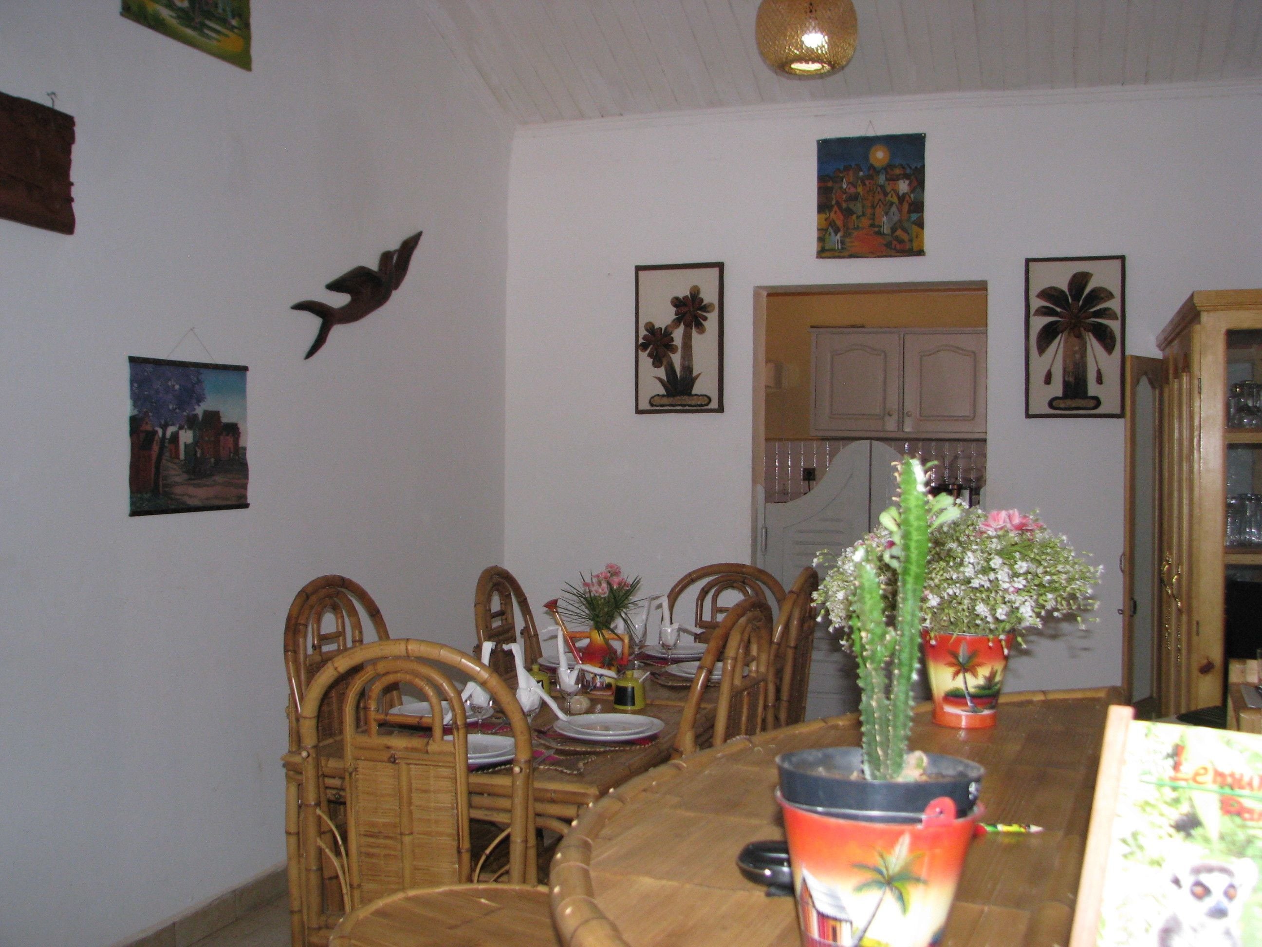 Uma sala de jantar com uma mesa de madeira, cadeiras e diversas decorações nas paredes, incluindo pinturas e uma escultura de pássaro.