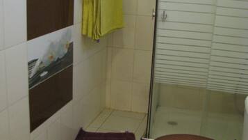 A bathroom with a toilet, a shower, and a glass-enclosed shower stall.