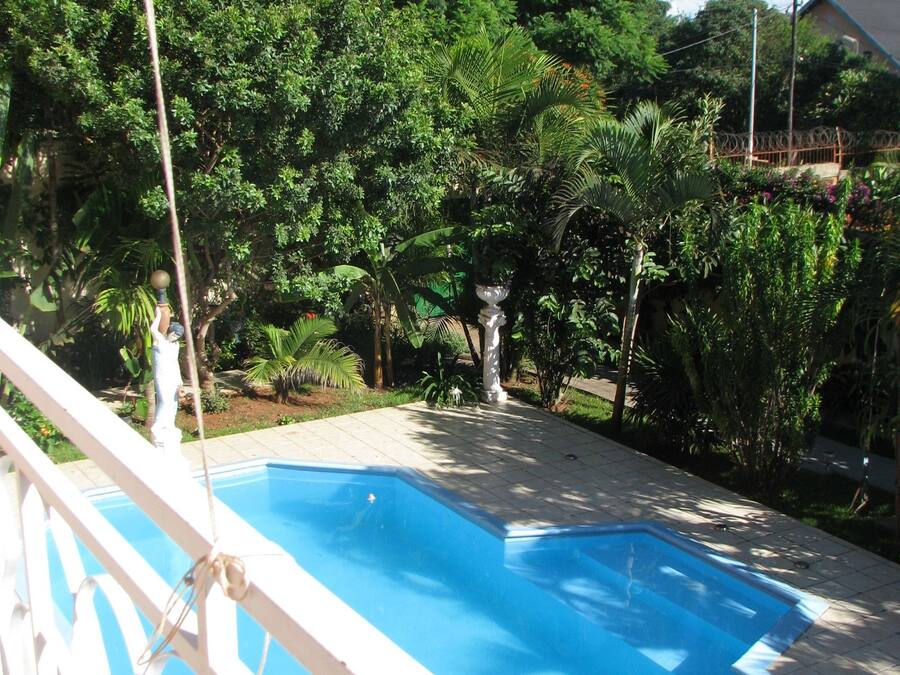 A swimming pool with a white railing, surrounded by lush greenery and trees.
