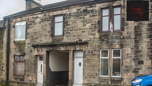 A two-story stone building with a sign reading "Klasse Living." - One Bedroom Apartment by Klass Living Serviced Accommodation Coatbridge - Albion Apartment with Wifi and Parking (Coatbridge)