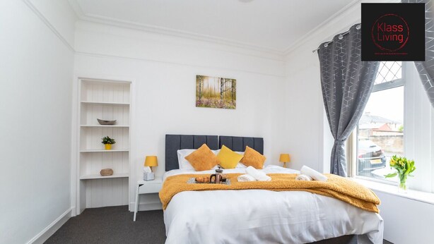 A neatly arranged bedroom with a bed, bedside tables, a shelf unit, and a window with curtains. - One Bedroom Apartment by Klass Living Serviced Accommodation Coatbridge - Albion Apartment with Wifi and Parking (Coatbridge)