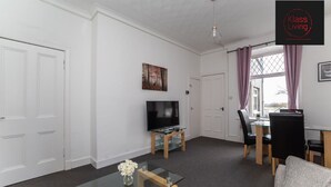 A modern living room with a flat-screen TV, glass coffee table, and a dining area with a table and chairs. - One Bedroom Apartment by Klass Living Serviced Accommodation Coatbridge - Albion Apartment with Wifi and Parking (Coatbridge)