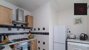 A compact kitchen with a gas stove, oven, microwave, and a washing machine. - One Bedroom Apartment by Klass Living Serviced Accommodation Coatbridge - Albion Apartment with Wifi and Parking (Coatbridge)