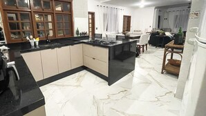 Eine moderne Küche mit Marmorboden, Holzschränken und einer zentralen Kochinsel.