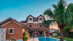 Ein zweistöckiges Haus mit Swimmingpool, Backsteinfassade und gepflegtem Rasen.