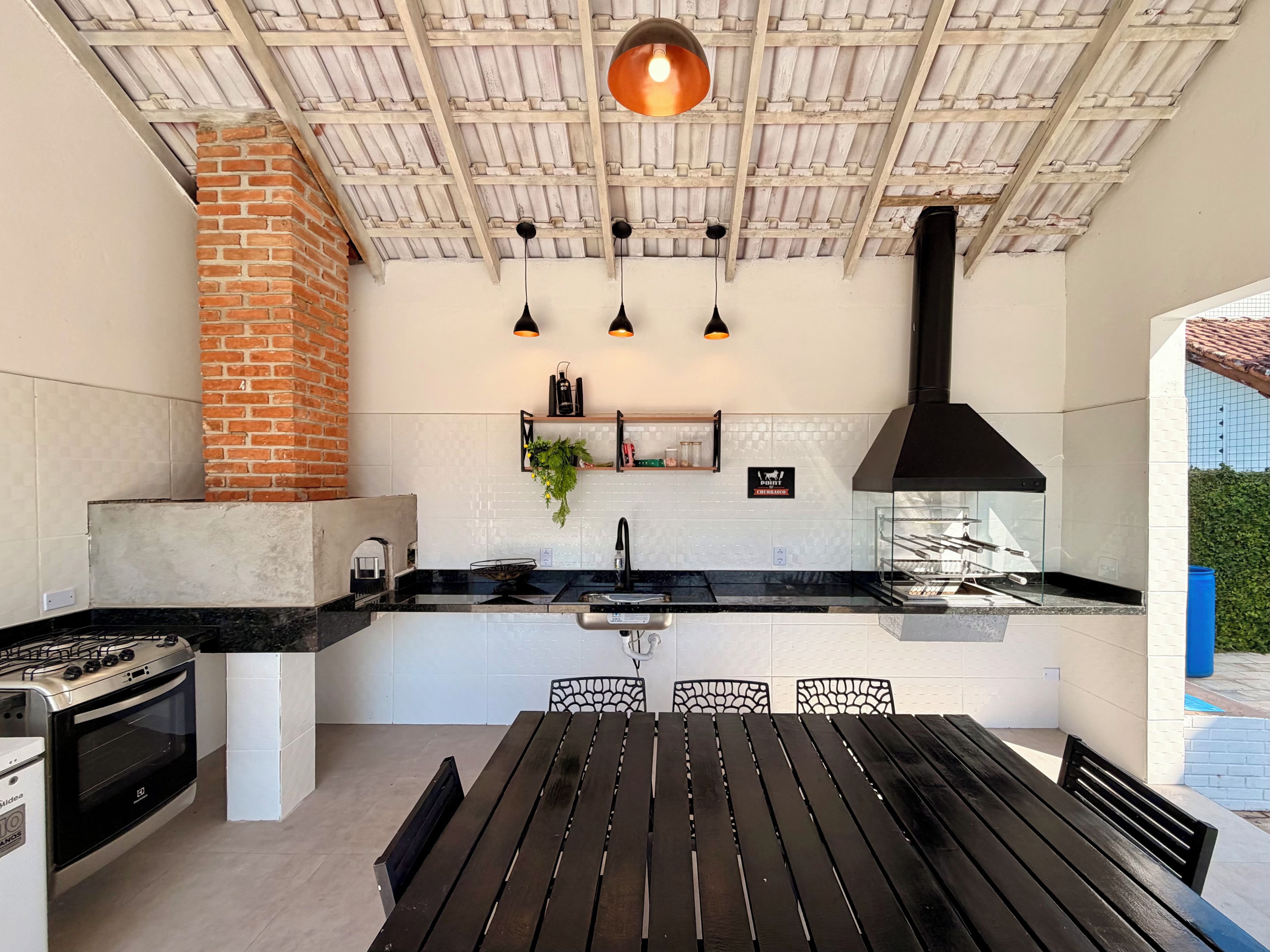 Una cocina exterior con horno de ladrillo, estufa a gas e iluminación colgante.