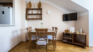 Ein Essbereich mit Holztisch, Stühlen, einem an der Wand montierten Fernseher und einer Holzhilfe mit Dekorationselementen.
