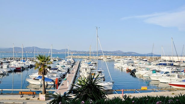 A marina with numerous boats docked, a clear sky, and a distant mountain range. - Escale au soleil Hôtel et Appartement (Fréjus)