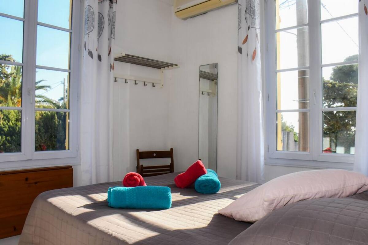 Une chambre à coucher avec un lit, une tête de lit en bois, un miroir et de grandes fenêtres.