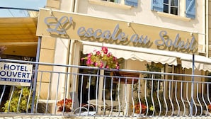 A hotel named "L'escalade au Soleil" with a balcony, outdoor seating, and a sign indicating it is a hotel. - Escale au soleil Hôtel et Appartement (Fréjus)