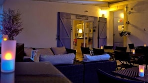 A cozy indoor seating area with a reception desk, wicker furniture, and candles. - Escale au soleil Hôtel et Appartement (Fréjus)