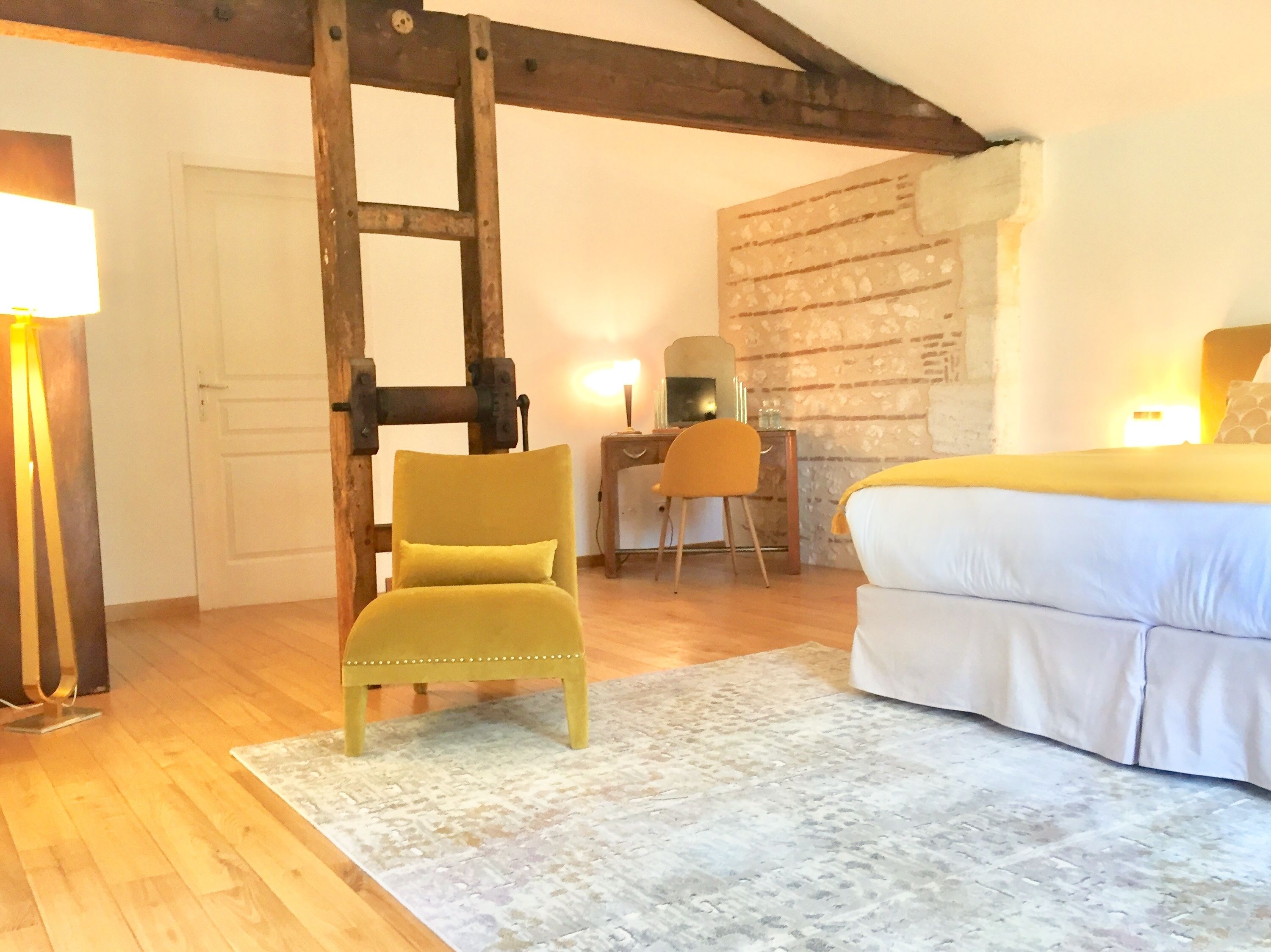 Un dormitorio con cama, escritorio, silla y estructura de vigas de madera.