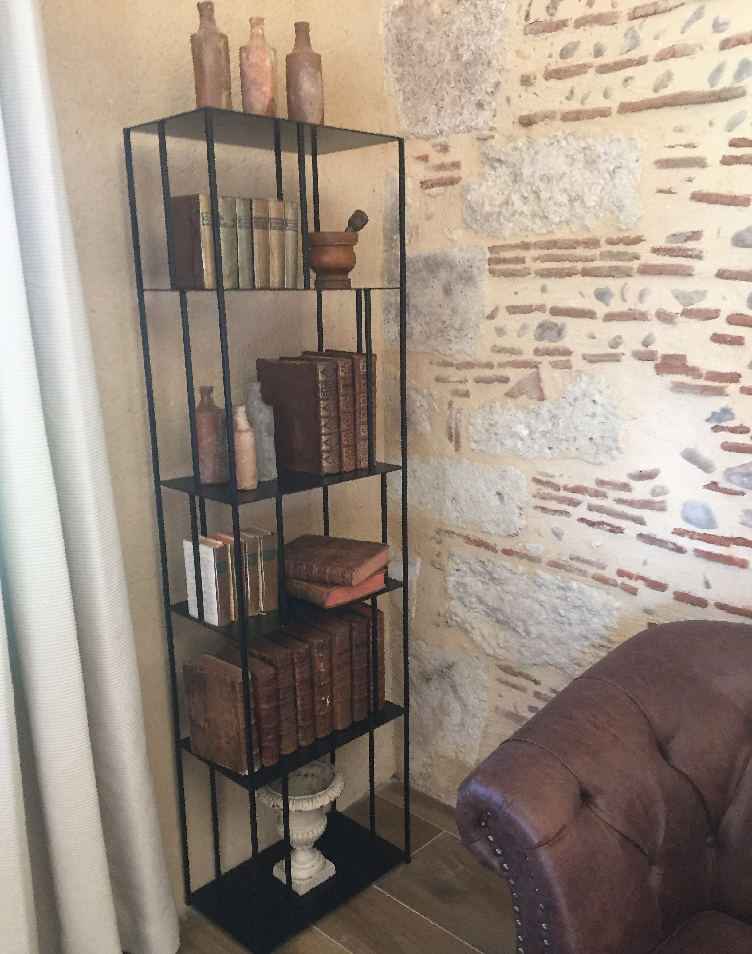 A bookshelf with various decorative items and books, positioned against a textured stone wall.