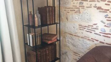 A bookshelf with various decorative items and books, positioned against a textured stone wall.
