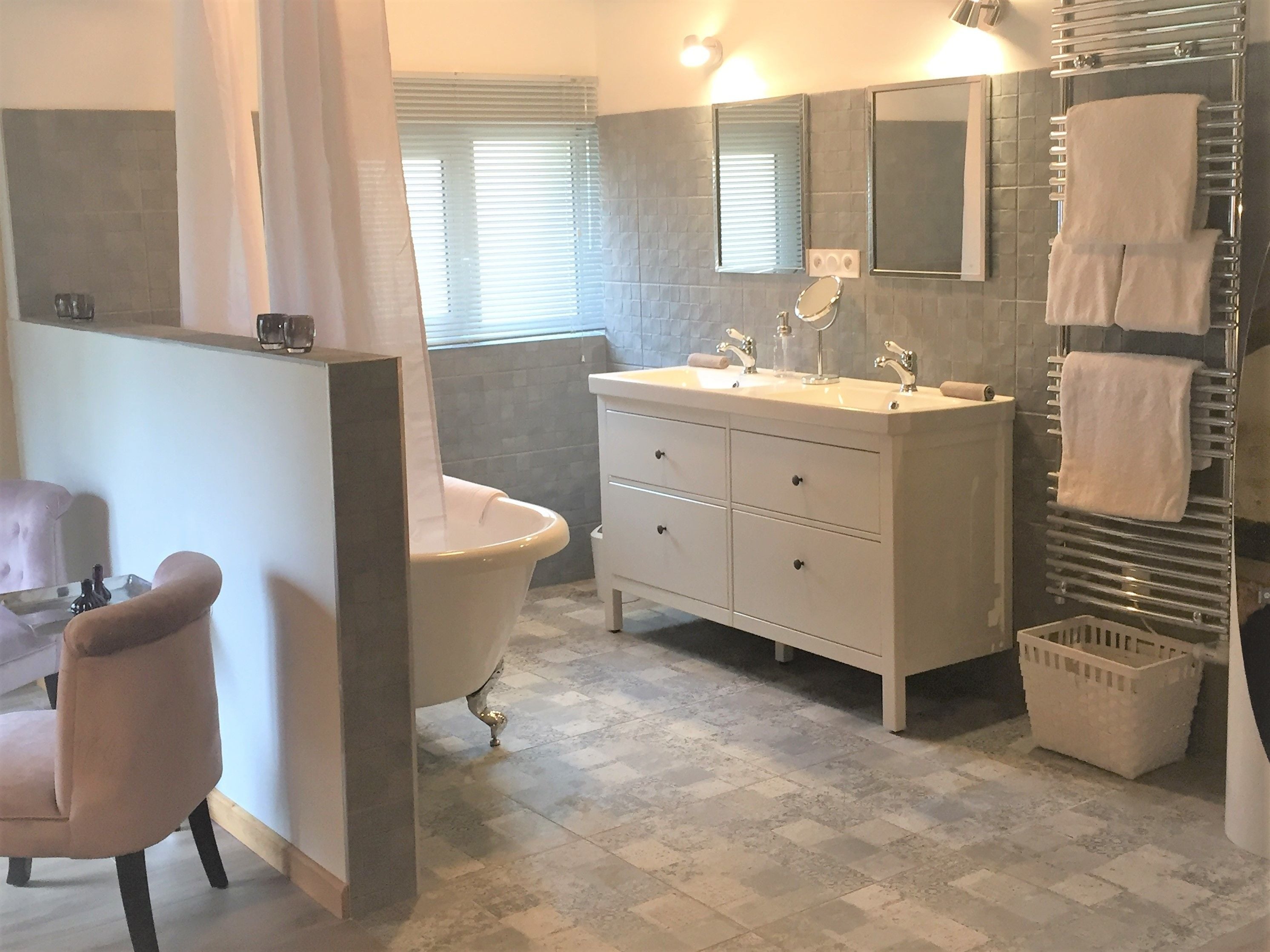 Un baño con bañera, tocador con espejo y perchero.