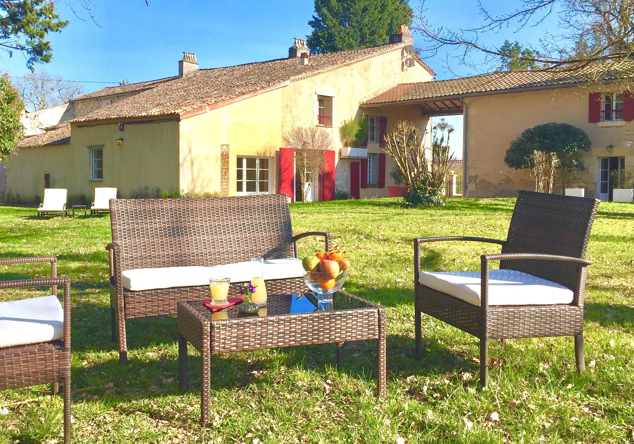 An outdoor seating area with wicker furniture and a table with fruit and drinks.
