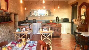 Un comedor acogedor con una mesa dispuesta para el desayuno, una cocina al fondo y una decoración rústica.