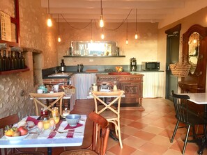 Un coin repas chaleureux avec une table mise pour le petit-déjeuner, une cuisine en arrière-plan et une décoration rustique.