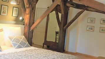 A bedroom with a bed, a wooden beam structure, and framed pictures on the wall.
